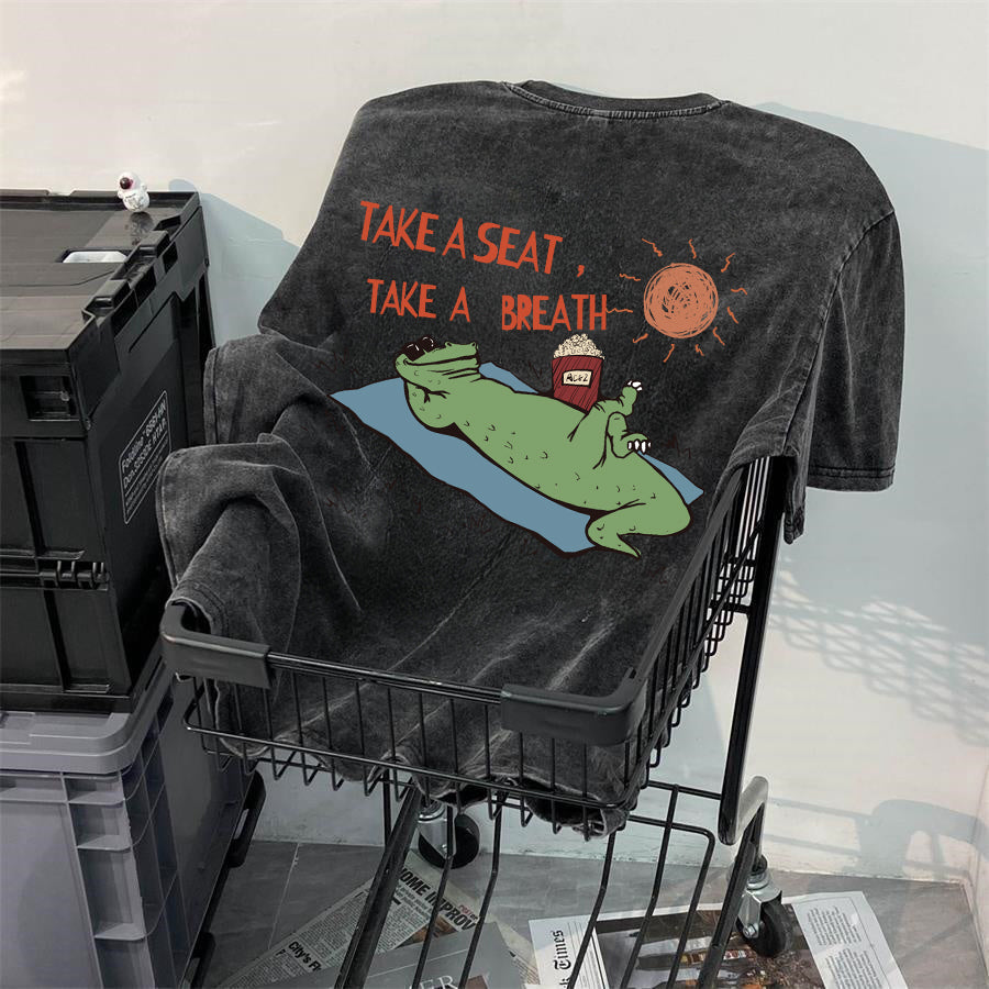 Close-up of funny crocodile character wearing sunglasses graphic print on vintage acid-wash fabric.