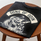 Lifestyle shot of the Vikingg Sons of Odin graphic t-shirt folded on a chair, dark aesthetic Norse streetwear.