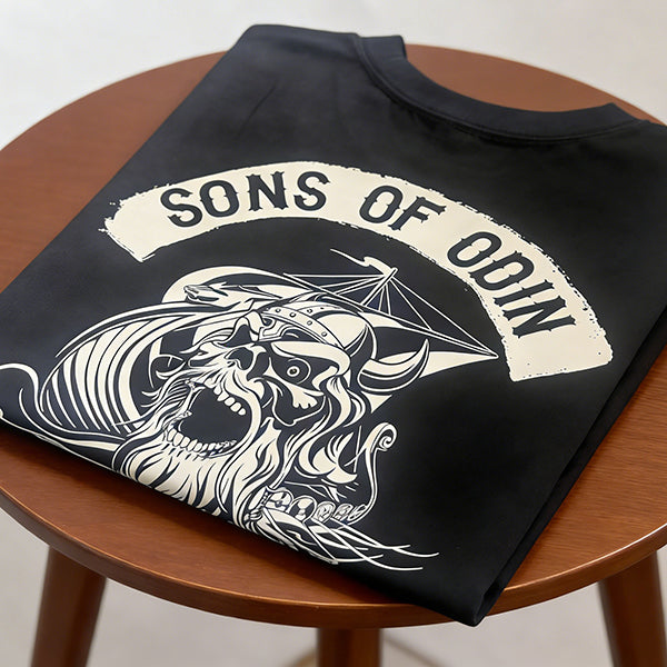 Lifestyle shot of the Vikingg Sons of Odin graphic t-shirt folded on a chair, dark aesthetic Norse streetwear.